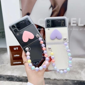 Samsung Z Flip case with heart decor and rainbow bead wrist strap in street style scene