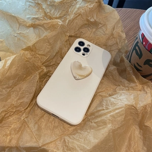 Close-up of cream liquid silicone iPhone case with 3D heart on a textured paper backdrop