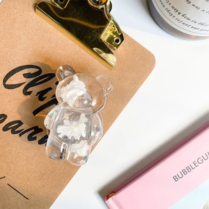 Macro detail of transparent resin bear phone stand with glitter and cream texture