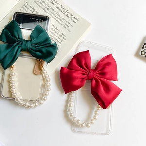 Detail of transparent phone case with large satin bow and luxury pearl wrist strap