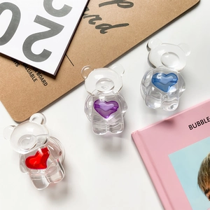 Close-up of cute transparent resin bear phone grips with colorful hearts on white desk