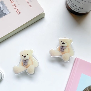 Detail of cute teddy bear acrylic folding phone grips on a minimalist desk setting