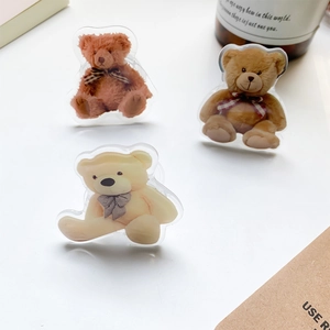 Three cute acrylic teddy bear phone grips in brown and cream on a white desk