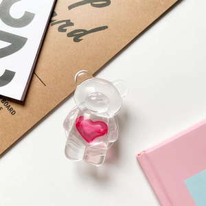Detailed close-up of a transparent bear-shaped phone grip with a pink heart center