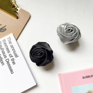 Detailed macro view of handmade satin rose fabric phone grips in black and silver finishes