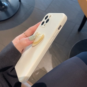 Close-up of cream silicone iPhone case featuring a marble textured heart phone grip