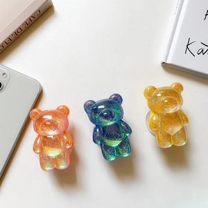 Detailed view of glitter bear phone grips in pink, blue, and yellow with resin finish