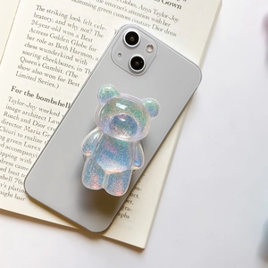 Detail view of a bear-shaped glitter phone grip with colorful sequins on a smartphone
