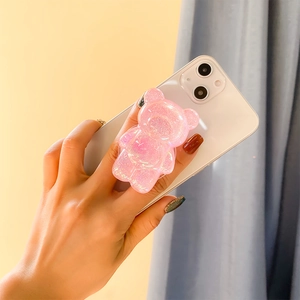 Close-up of pink glitter bear phone grip with sparkling sequins on a white smartphone