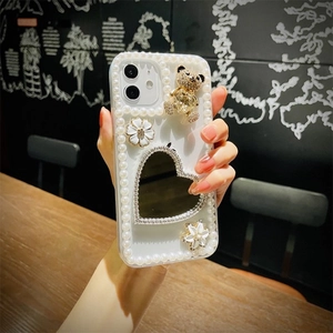 Detail of luxury iPhone case featuring pearls, heart mirror and a 3D rhinestone bear charm