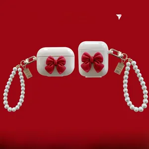 White AirPods case featuring a 3D red bow detail and an elegant pearl chain strap