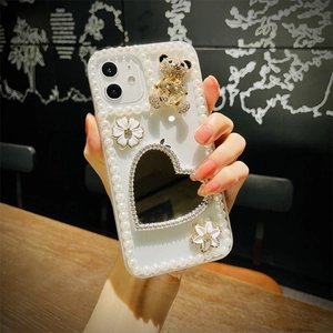 Detail of iPhone case featuring a heart-shaped mirror, 3D bear, and pearl accents