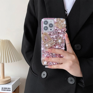 Detailed luxury iPhone case with pink crystals, crown, and pearl flower charms