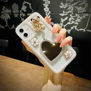 Detail of iPhone case featuring a 3D golden bear and heart-shaped mirror with pearl edges