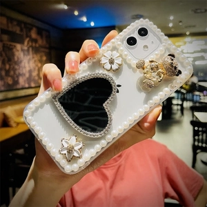 Close-up of pearl edges and black heart mirror with gold diamond bear on phone case
