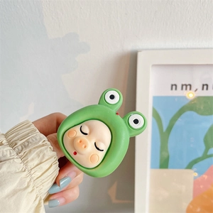 Close-up of cute green frog-themed cartoon pig phone grip holder held in hand