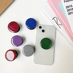 Macro detail of six glitter-filled round phone grips in red blue silver and purple