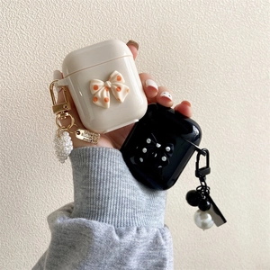 Dettaglio custodia AirPods in silicone con fiocco 3D, ciondoli di perle e piastrine