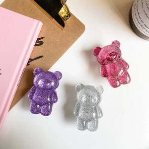 Glittery bear phone grips in purple, silver, and pink set on a soft pastel background