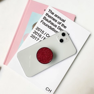 Close-up of bright red glitter resin phone grip holder on white mobile device