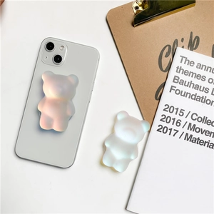 Macro view of 3D bear phone grip with iridescent pearl finish on a white smartphone