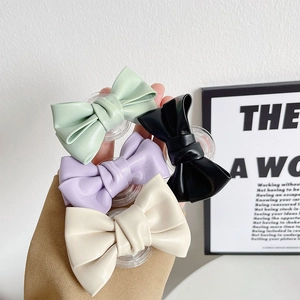 Nahaufnahme von vier bunten Leder-Schleifen-Handyhaltern in Mint, Lila, Schwarz und Beige