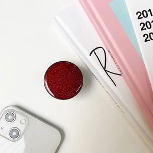 Detailed view of red glitter phone grip on a desk with aesthetic background decor