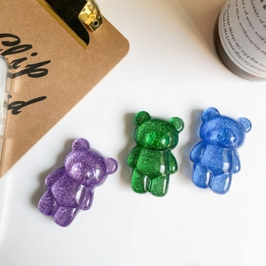 Detailed view of glitter resin bear phone grips in purple, green, and blue colors