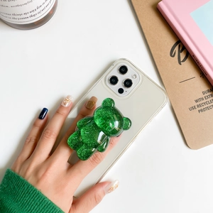 Close-up of a cute glittery emerald green bear-shaped collapsible phone grip on a clear case
