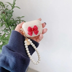 Creamy white AirPods Pro case with red bow and elegant pearl chain hand strap