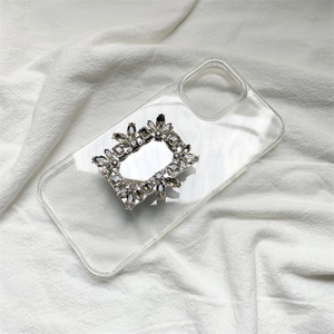 Close-up of a luxury square crystal buckle on a clear phone case over white fabric