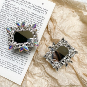 Close-up of luxury rhinestones and diamond mirror phone stand on vintage book pages