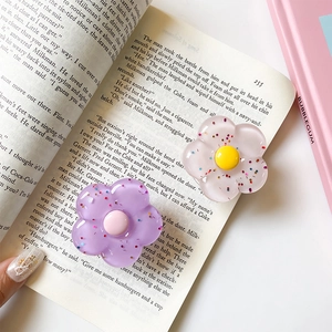 Dettaglio del supporto per telefono a fiore 3D in resina glitterata su un libro