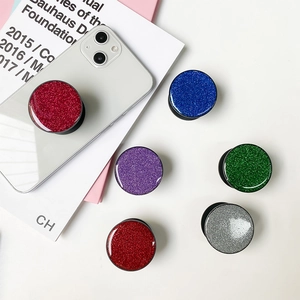 Glitter resin round phone socket grips in vibrant colors on a white minimalist desk