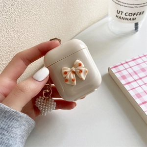 Custodia AirPods bianco crema con fiocco 3D e un ciondolo delicato con perla a cuore
