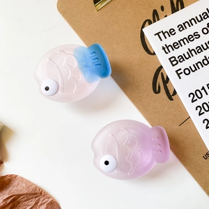 Close-up of cute matte fish-shaped phone grip accessories in pink, blue, and purple colors