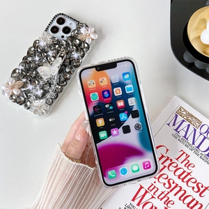 Detailed close-up of luxury iPhone case with rhinestones, pearl flowers, and crystal charm