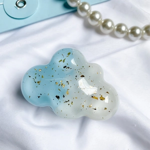Blue and white cloud phone grip with gold foil flakes on a soft textured background