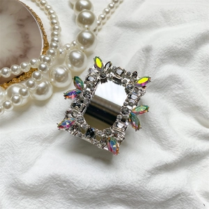 Detail showing retractable mirror phone grip with luxury rhinestones on white fabric