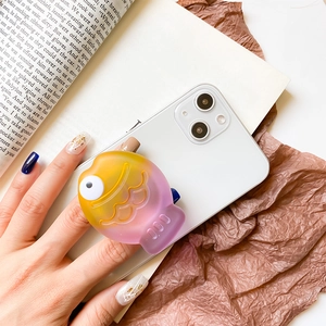 Detailed view of a 3D fish-shaped phone grip with yellow to pink gradient on a smartphone