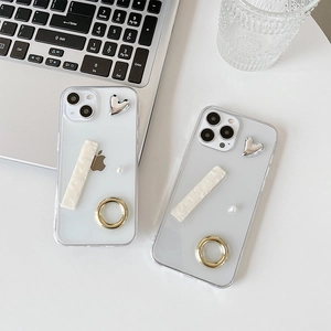 Detail view of transparent iPhone case with silver heart and pearl ring holder on a desk