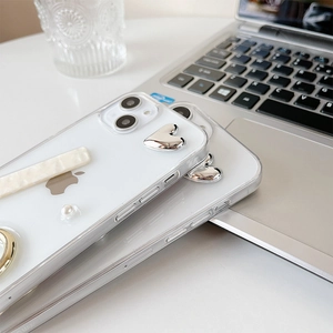 Detail view of transparent iPhone case featuring silver hearts, pearls and ring holder