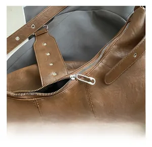 Close-up of caramel PU leather bag with silver pin-style zipper and stitching detail