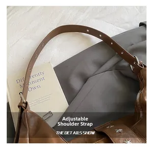 Detail of brown leather tote bag featuring adjustable shoulder strap with metal eyelets