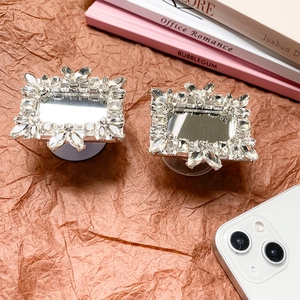 Close-up of luxury rhinestone square mirror phone socket grip on vintage paper background