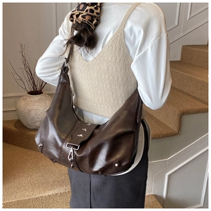 Detail of dark brown tote bag featuring silver star studs and punk buckle accents