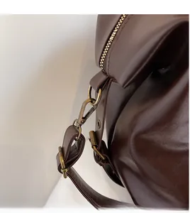 Close-up of vintage bronze metal hook and durable brown leather strap on tote bag