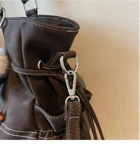 Detail of silver metal hook and D-ring on dark brown leather tote bag with white stitching