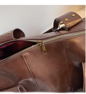 Detail of dark brown leather tote bag with antique gold zipper and rivets decoration