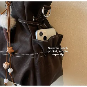 Detail of deep brown tote bag with contrast stitching and side pocket for phone